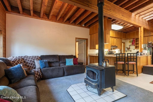 living room featuring light carpet, beam ceiling, wooden ceiling, a wood stove, and wood walls