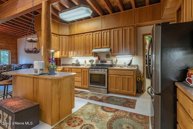 kitchen with wood walls, pendant lighting, a kitchen island, and stainless steel appliances