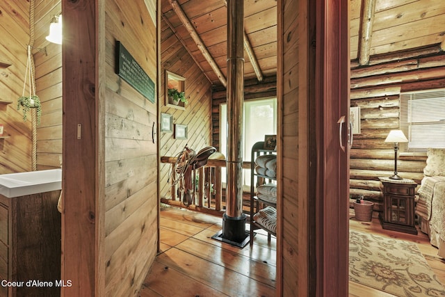 corridor featuring rustic walls, vaulted ceiling with beams, wooden ceiling, and hardwood / wood-style floors