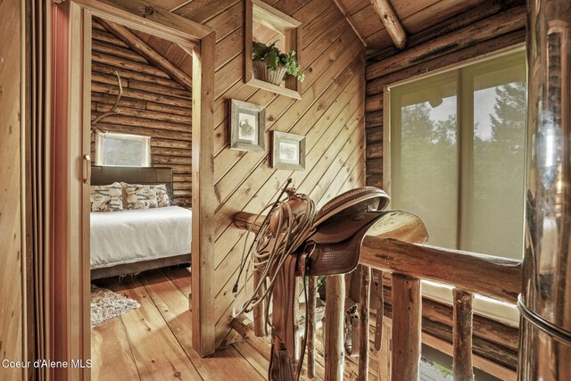 interior space featuring beamed ceiling, light hardwood / wood-style floors, rustic walls, wood walls, and wooden ceiling