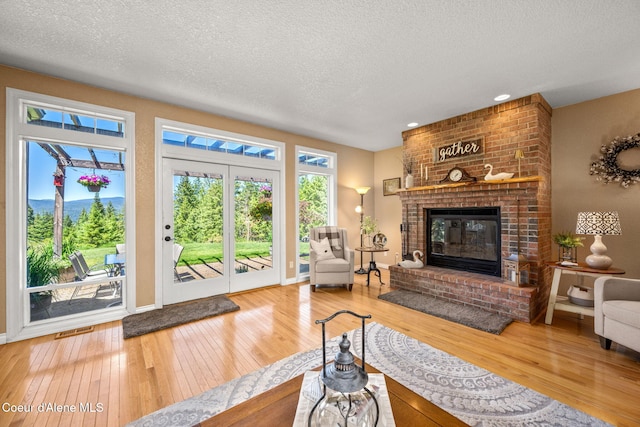 17536 W Julia Dr, Hauser, ID 83854 - living area with hardwood / wood-style floors, a textured ceiling, plenty of natural light, a brick fireplace, and recessed lighting