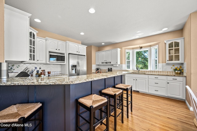 17536 W Julia Dr, Hauser, ID 83854 - kitchen featuring stainless steel appliances, a peninsula, a breakfast bar area, tasteful backsplash, and recessed lighting
