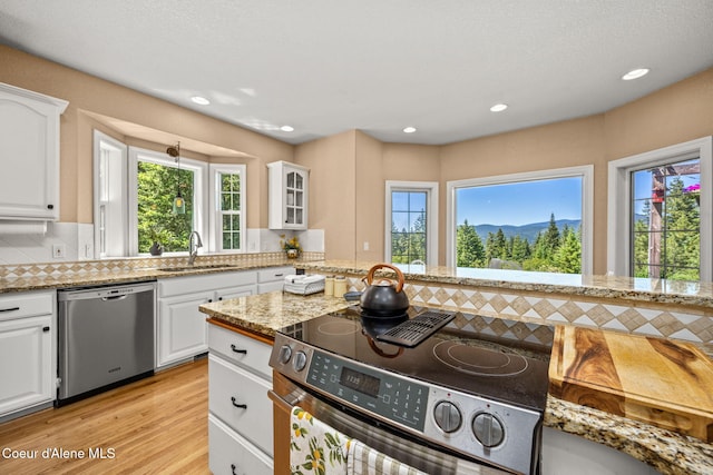 17536 W Julia Dr, Hauser, ID 83854 - kitchen with stainless steel appliances, plenty of natural light, tasteful backsplash, white cabinets, and recessed lighting