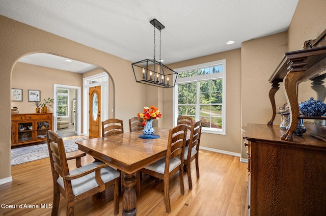 17536 W Julia Dr, Hauser, ID 83854 - dining room with arched walkways, light wood-style flooring, a chandelier, recessed lighting, and a textured wall