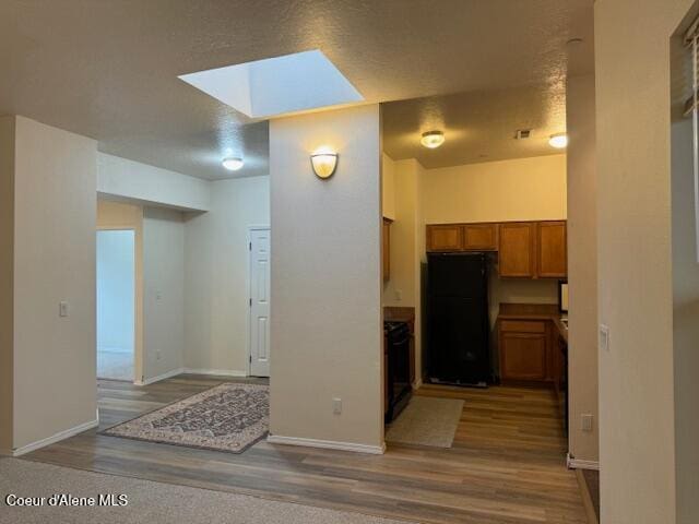 kitchen with a skylight, black refrigerator, and wood-type flooring