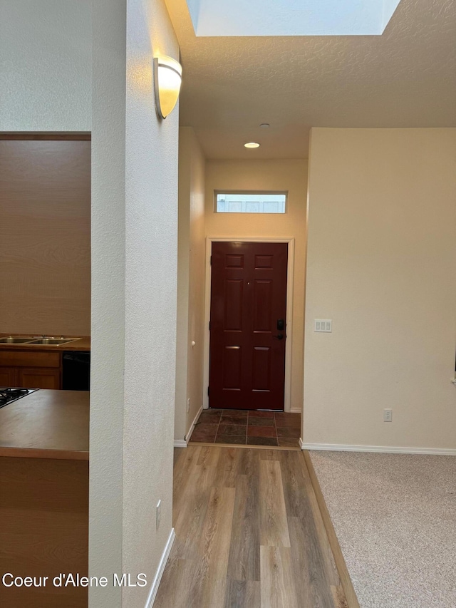 foyer featuring a skylight, a textured ceiling, and hardwood / wood-style floors