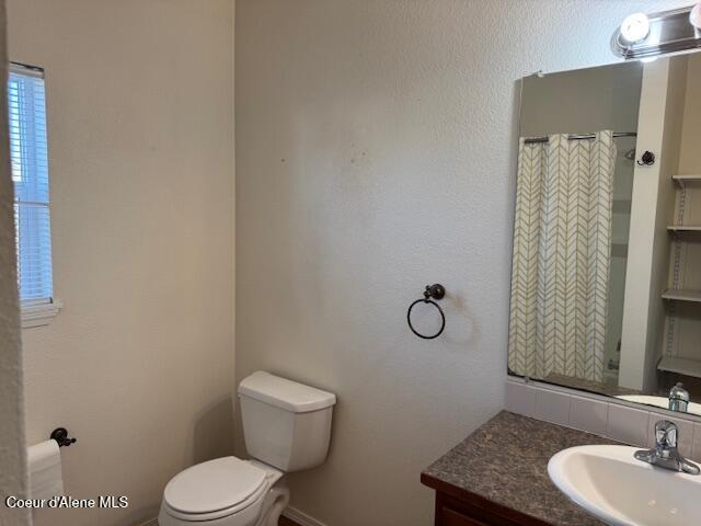 bathroom featuring toilet, vanity, and a shower with curtain