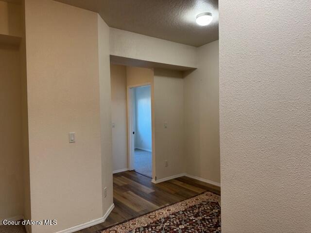 hall with a textured ceiling and dark hardwood / wood-style floors