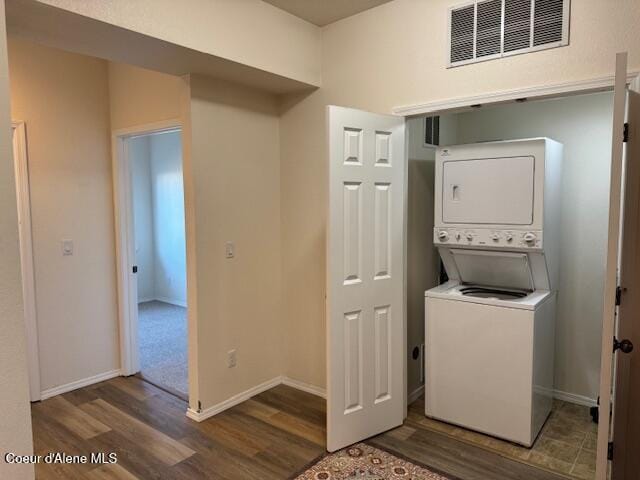 washroom featuring stacked washer and clothes dryer and dark hardwood / wood-style floors