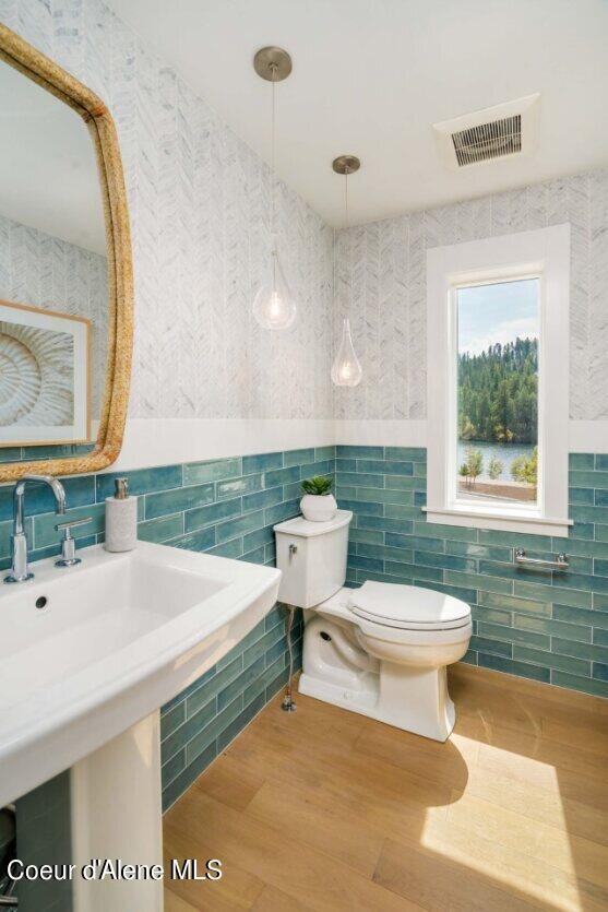 bathroom featuring tile walls, hardwood / wood-style flooring, and toilet