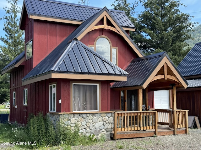 chalet / cabin featuring covered porch, metal roof, and stone siding