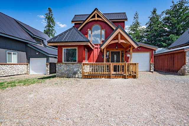 view of front facade featuring an attached garage, stone siding, board and batten siding, gravel driveway, and metal roof