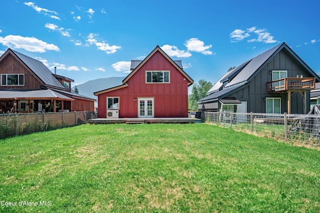 rear view of property with board and batten siding, a yard, fence, and french doors