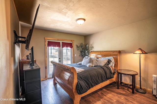 bedroom with a textured wall, access to exterior, french doors, baseboards, and wood finished floors