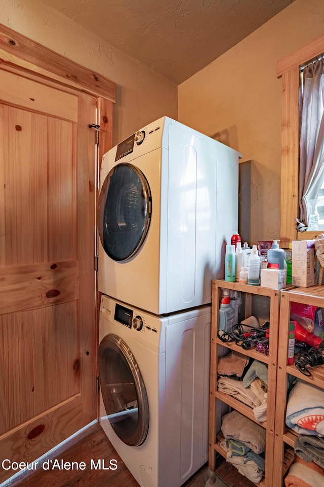 washroom featuring laundry area, stacked washer and dryer, and wood finished floors