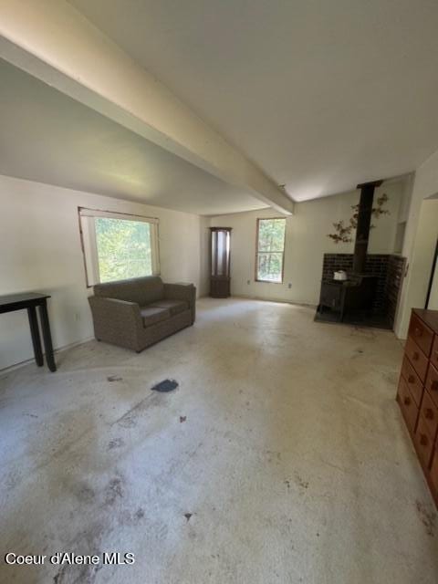 unfurnished living room with beamed ceiling and a wood stove