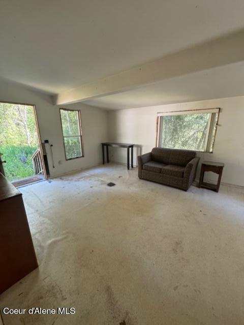 interior space with light colored carpet and beamed ceiling