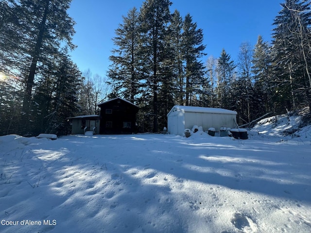 yard layered in snow featuring a storage shed