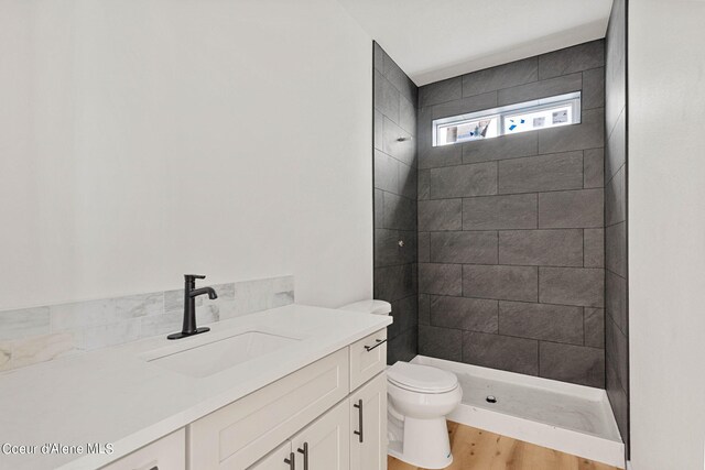 bathroom featuring tiled shower, toilet, hardwood / wood-style floors, and vanity