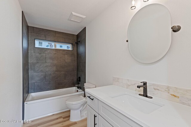 full bathroom featuring vanity, tiled shower / bath combo, hardwood / wood-style flooring, and toilet