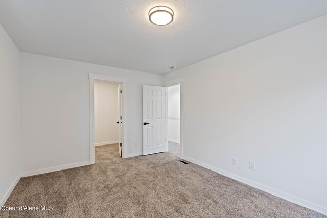 unfurnished bedroom with a spacious closet and carpet