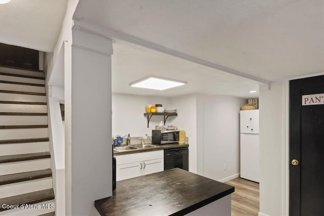 kitchen featuring white cabinetry, black dishwasher, sink, white fridge, and light hardwood / wood-style floors