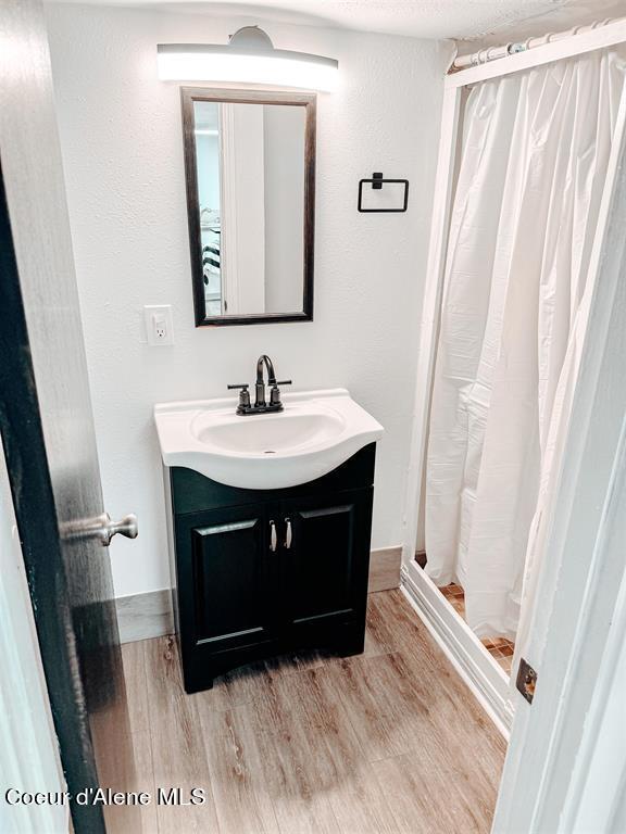 bathroom featuring vanity, wood-type flooring, a textured ceiling, and a shower with curtain