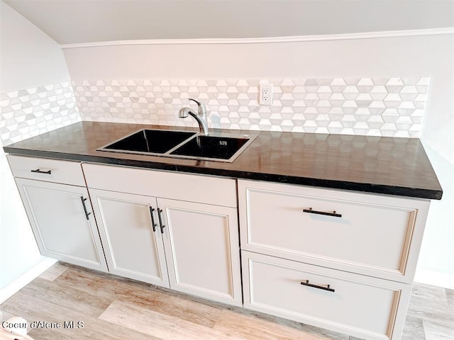 kitchen featuring light hardwood / wood-style floors, sink, decorative backsplash, and white cabinets