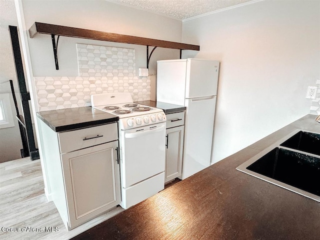 kitchen featuring sink, a textured ceiling, light wood-type flooring, white appliances, and backsplash