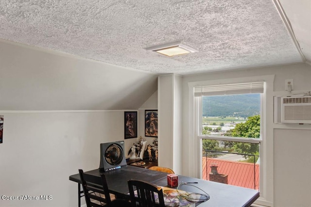 dining space with a wall mounted air conditioner, lofted ceiling, and a textured ceiling