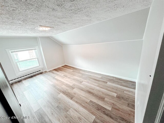 bonus room with lofted ceiling, light wood-type flooring, a textured ceiling, and a baseboard heating unit