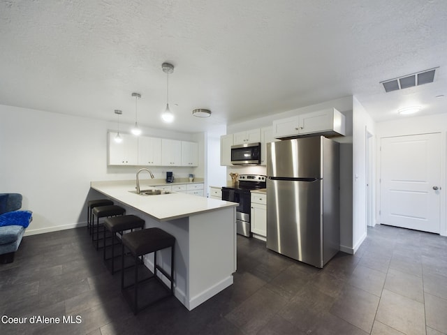 kitchen with pendant lighting, white cabinets, sink, appliances with stainless steel finishes, and kitchen peninsula