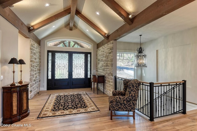 foyer featuring beamed ceiling, high vaulted ceiling, a notable chandelier, and light hardwood / wood-style floors