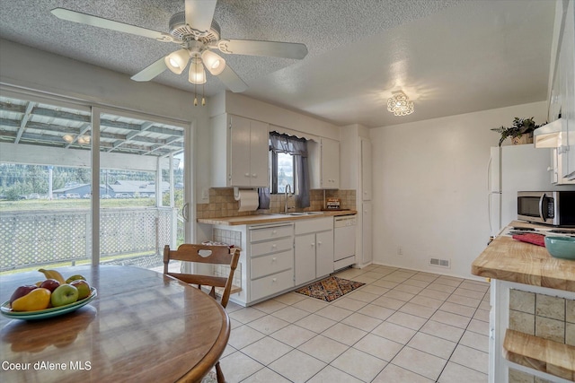 kitchen featuring light tile patterned flooring, sink, white cabinetry, tasteful backsplash, and dishwasher