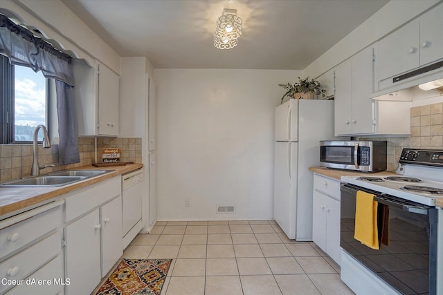 kitchen with sink, white appliances, light tile patterned floors, white cabinetry, and tasteful backsplash