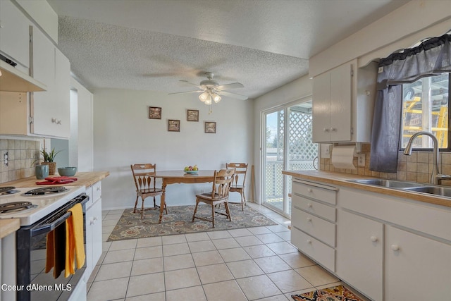 kitchen featuring light tile patterned floors, white electric range oven, sink, and white cabinets