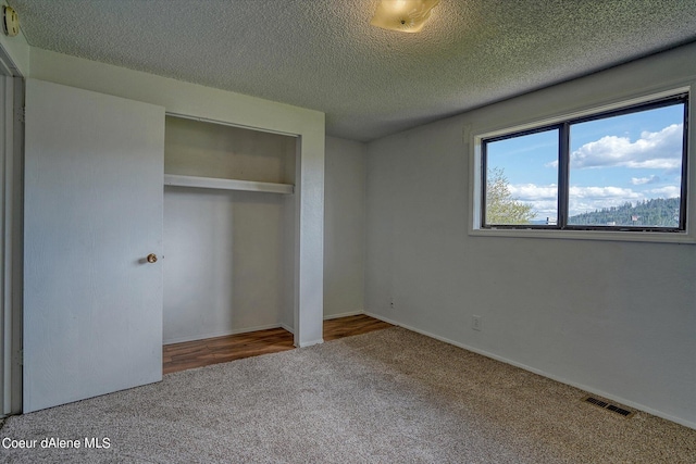 unfurnished bedroom with carpet floors, a closet, and a textured ceiling