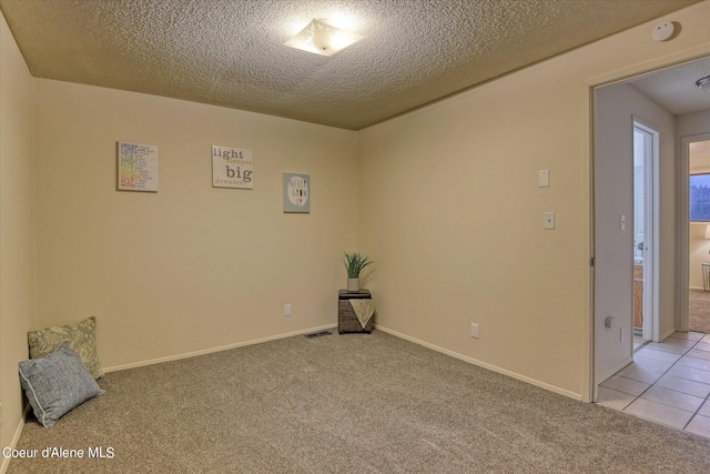 spare room featuring light carpet and a textured ceiling