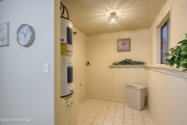 laundry room featuring electric water heater, a textured ceiling, and light tile patterned floors