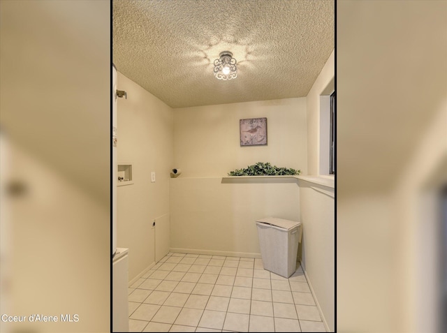 laundry room featuring washer hookup, light tile patterned floors, and a textured ceiling