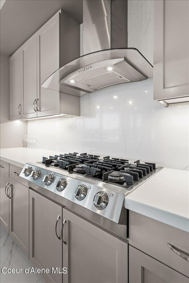 kitchen featuring gray cabinetry, stainless steel gas stovetop, extractor fan, and backsplash