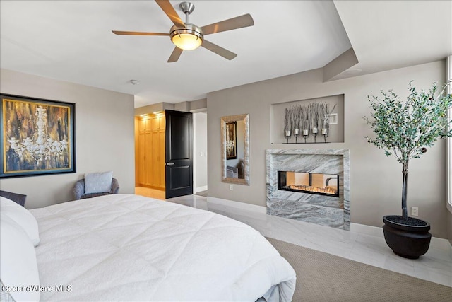 bedroom with ceiling fan, a high end fireplace, and connected bathroom