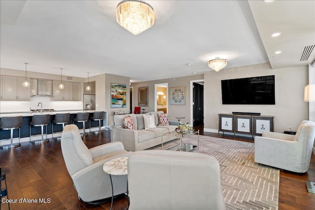 living room with a notable chandelier, sink, and dark hardwood / wood-style floors