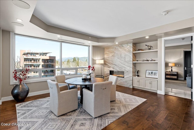 dining room with wood-type flooring, built in features, and a fireplace