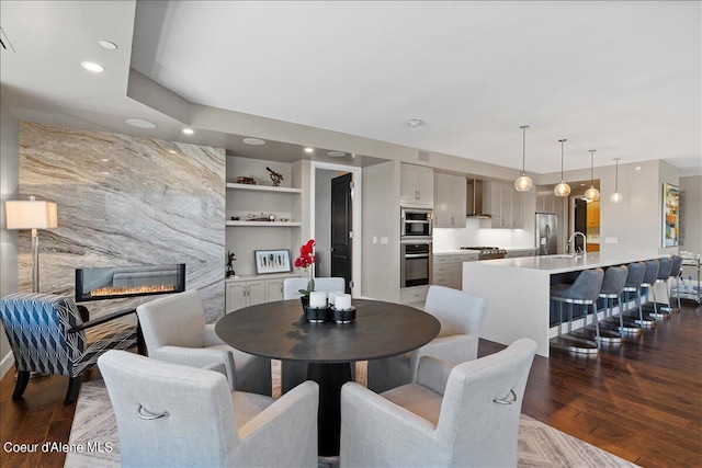 dining space with sink, a fireplace, built in features, and dark hardwood / wood-style floors