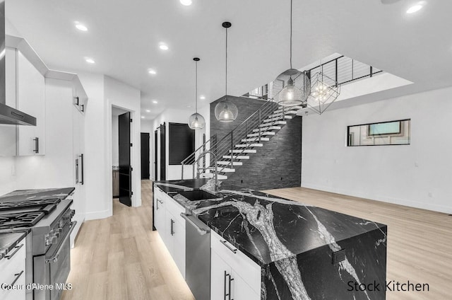 kitchen with white cabinets, pendant lighting, sink, and dark stone counters