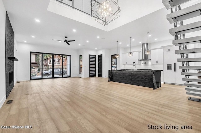 unfurnished living room featuring a fireplace, light hardwood / wood-style flooring, sink, and ceiling fan with notable chandelier