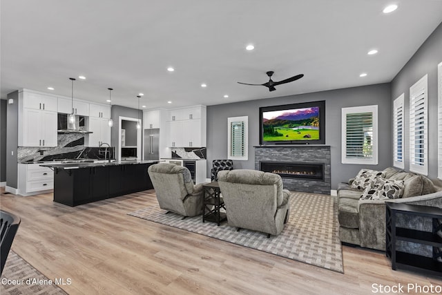 living area featuring recessed lighting, a fireplace, light wood-style flooring, and ceiling fan