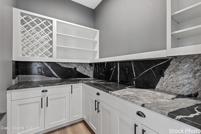 kitchen featuring light wood finished floors, tasteful backsplash, dark stone countertops, white cabinetry, and open shelves