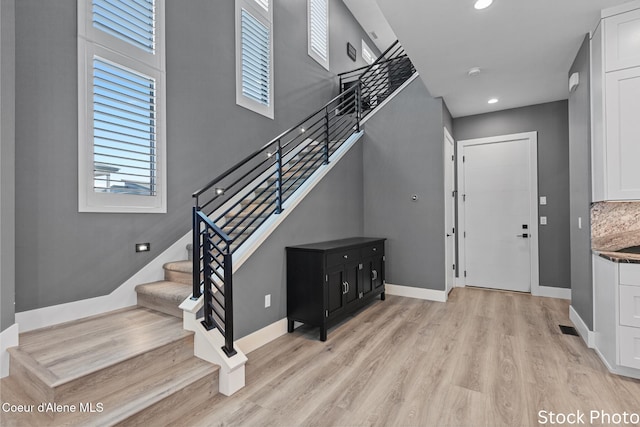 entrance foyer featuring visible vents, baseboards, stairway, light wood-type flooring, and recessed lighting